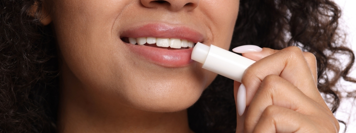 Vrouw brengt lippenbalsem in stickvorm aan